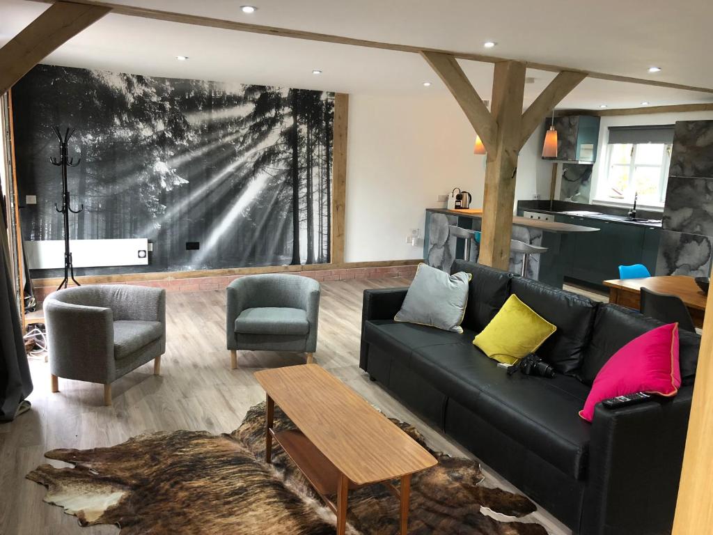 a living room with a black couch and chairs at Finlaystone Family Barn in Port Glasgow