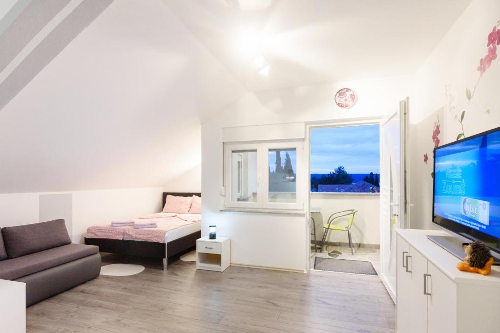 een witte woonkamer met een bank en een televisie bij Apartmani Orhideja in Gornji Karin