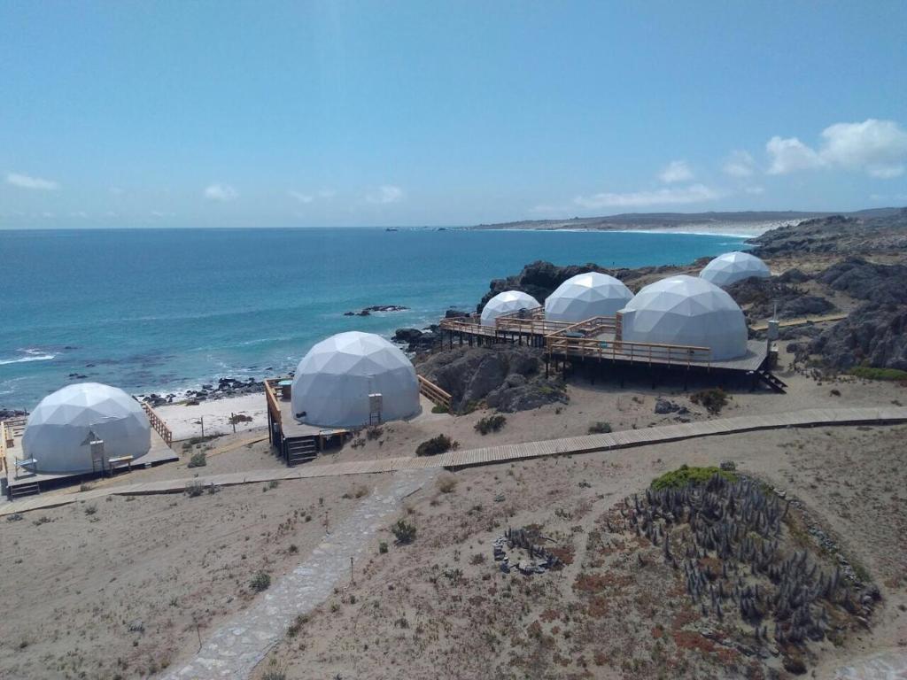 un grupo de cúpulas en una playa junto al océano en Kunza Kamanchacos, en Punta de Choros