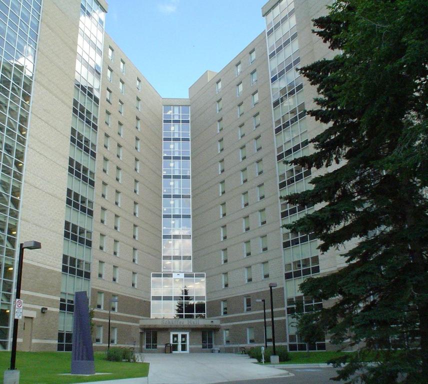 un gran edificio de oficinas con un árbol delante en University of Alberta - Accommodation en Edmonton