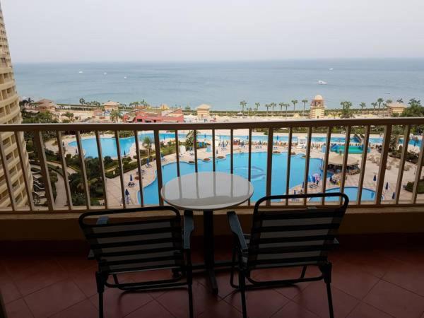 a balcony with a table and chairs and a view of the beach at Apartment in Porto Sokhna Pyramids for Families in Ain Sokhna