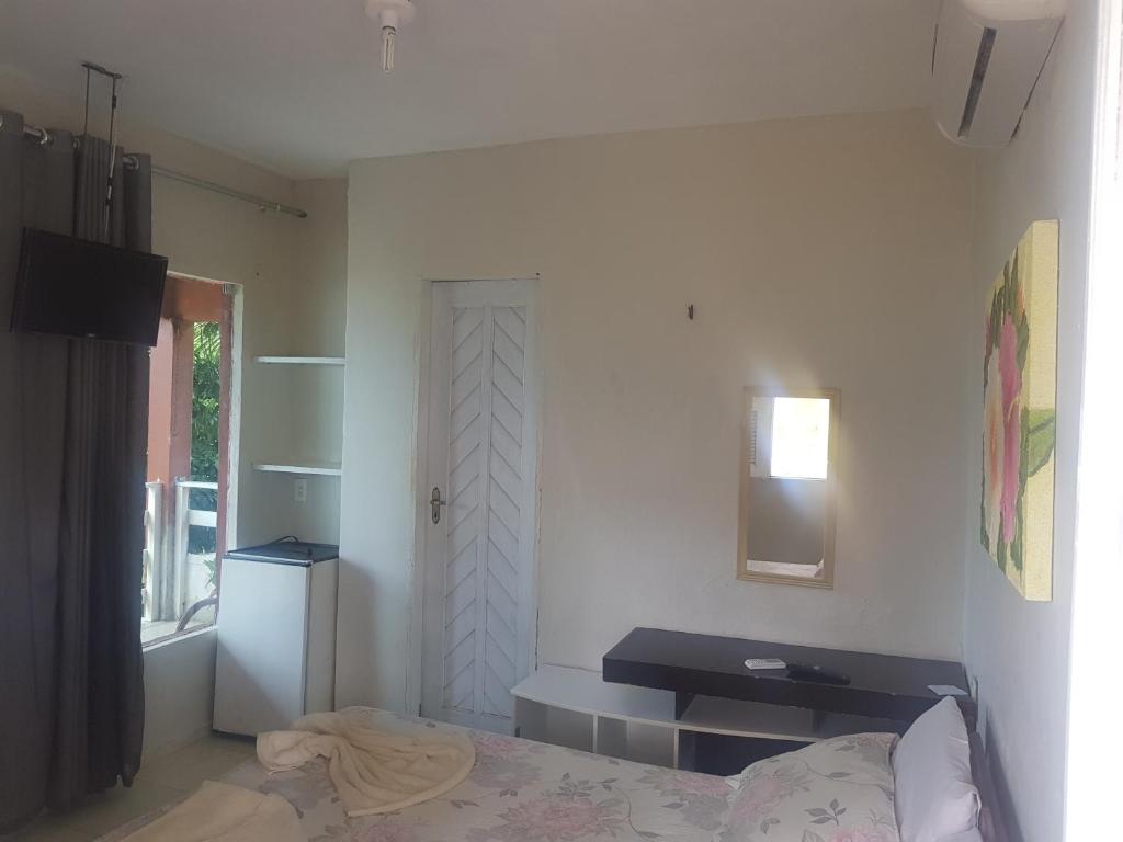 a bedroom with a bed and a desk and a window at Pousada e Restaurante Sombra dos Coqueiros in Trairi