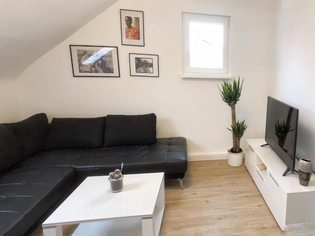 a living room with a black couch and a tv at Hugo18 Boardinghouse in Kandel