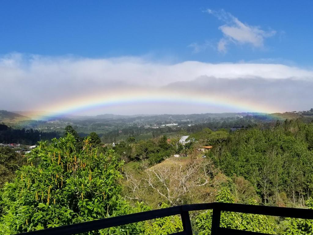 Ein Regenbogen über einer Stadt in der Unterkunft Hotel Monte Campana Heredia in Birrí