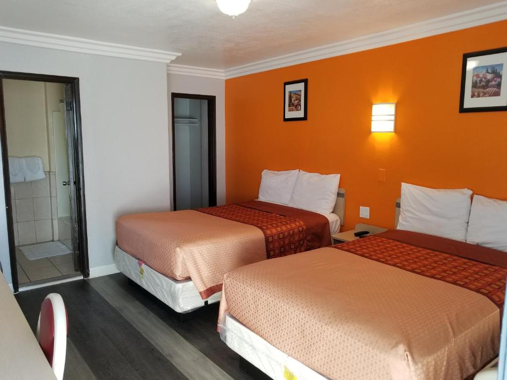 two beds in a hotel room with orange walls at Value Inn Hollywood in Los Angeles
