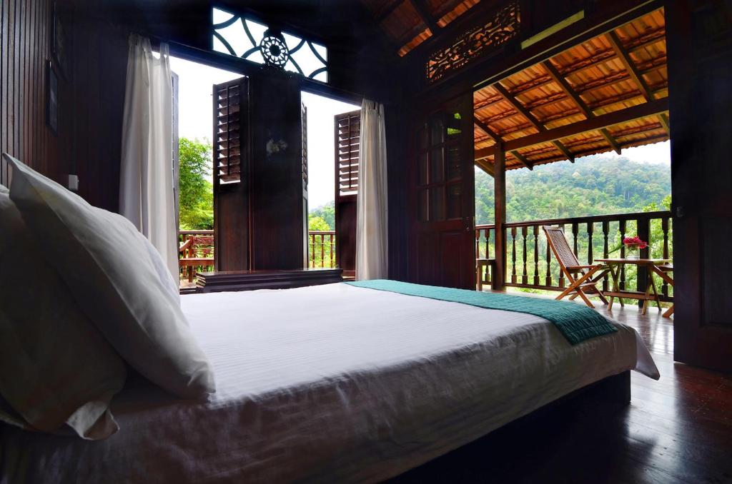 a bedroom with a bed in a room with a balcony at The Dusun in Seremban