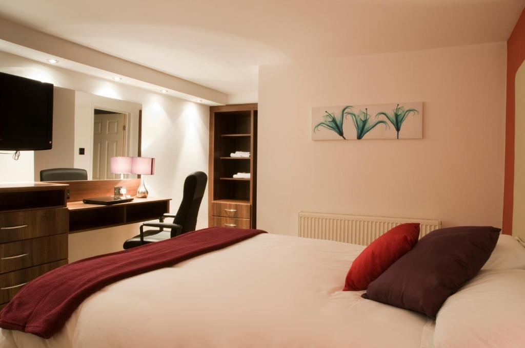 a bedroom with a bed with a desk and a chair at Haveli Hotel in Hensol