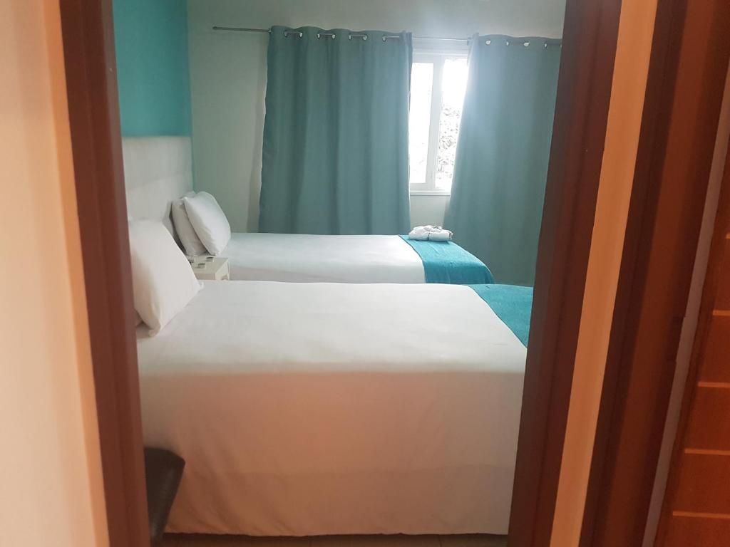 マプトにあるOrquidea GuestHouse Spa & Restaurantの青いカーテンが備わる客室のベッド2台
