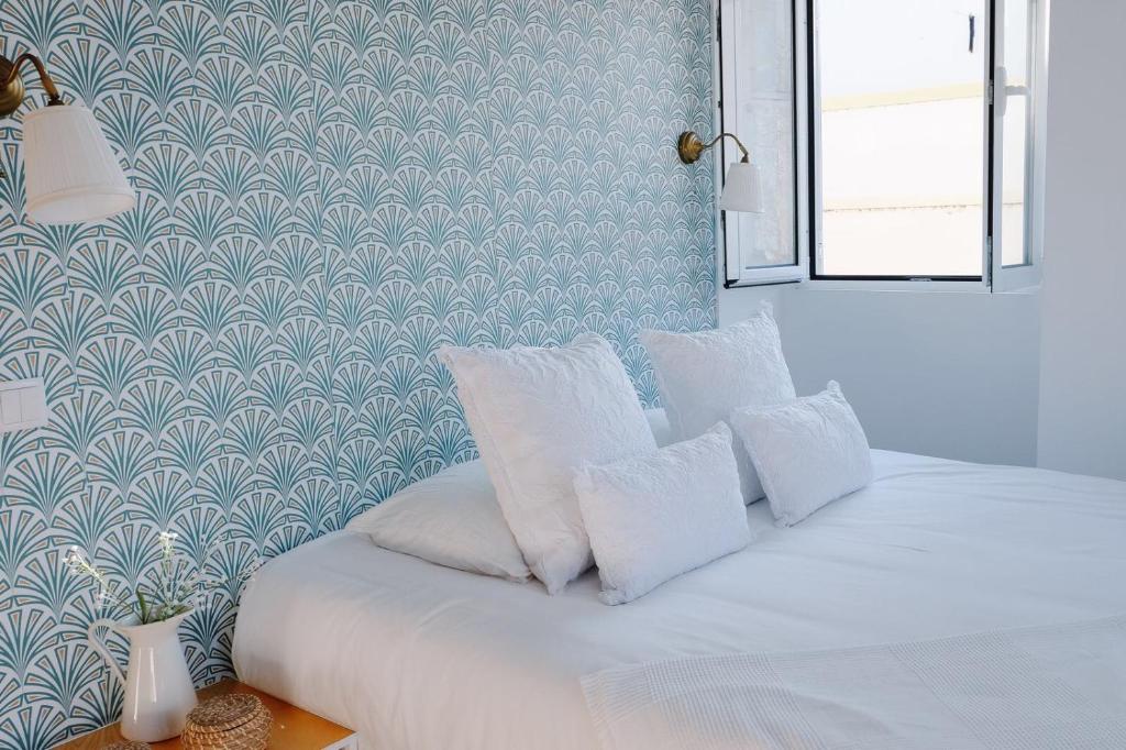 um quarto com uma cama com almofadas brancas em Casas de Mar - Búzio em Olhão