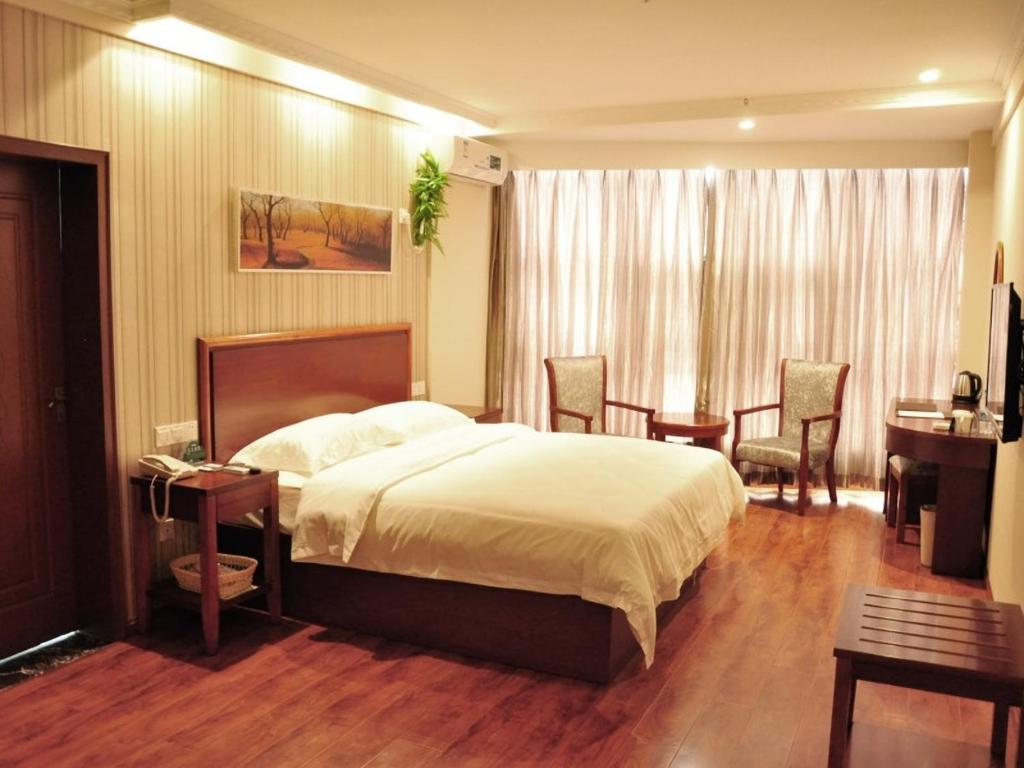 Un dormitorio con una cama y una mesa y sillas. en GreenTree Inn Anhui Hefei Mengcheng Road Beierhuan Express Hotel, en Hefei