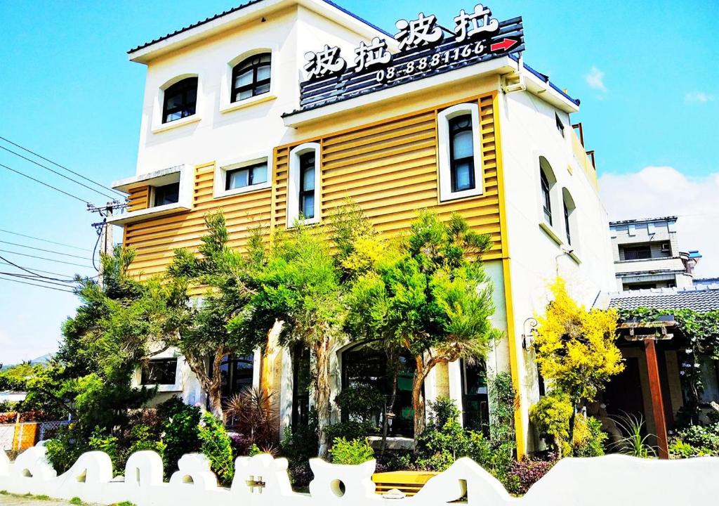 a yellow and white building with trees in front of it at Borabora B&B in Nanwan