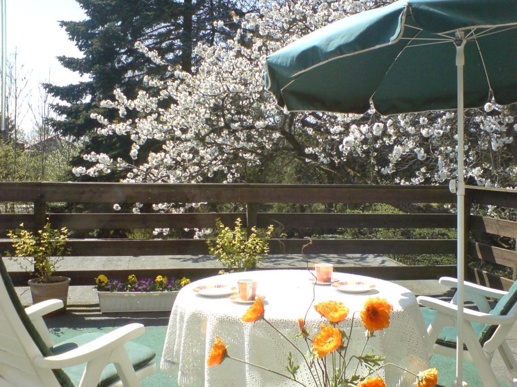 a table and chairs with an umbrella and flowers at Zur Kajüte in Butjadingen