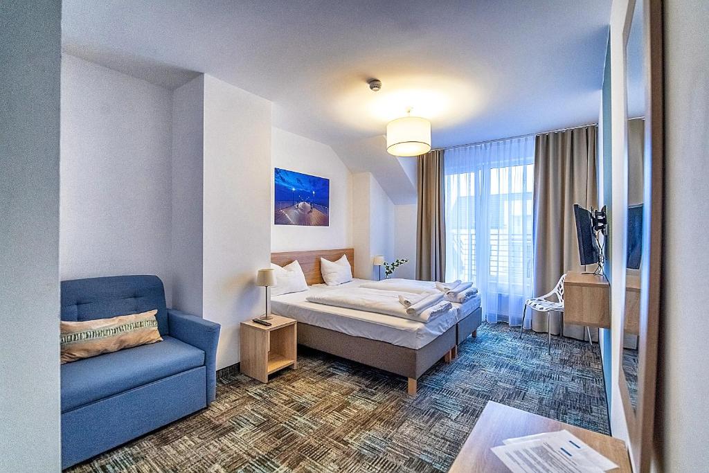a hotel room with a bed and a blue couch at Siesta in Grzybowo