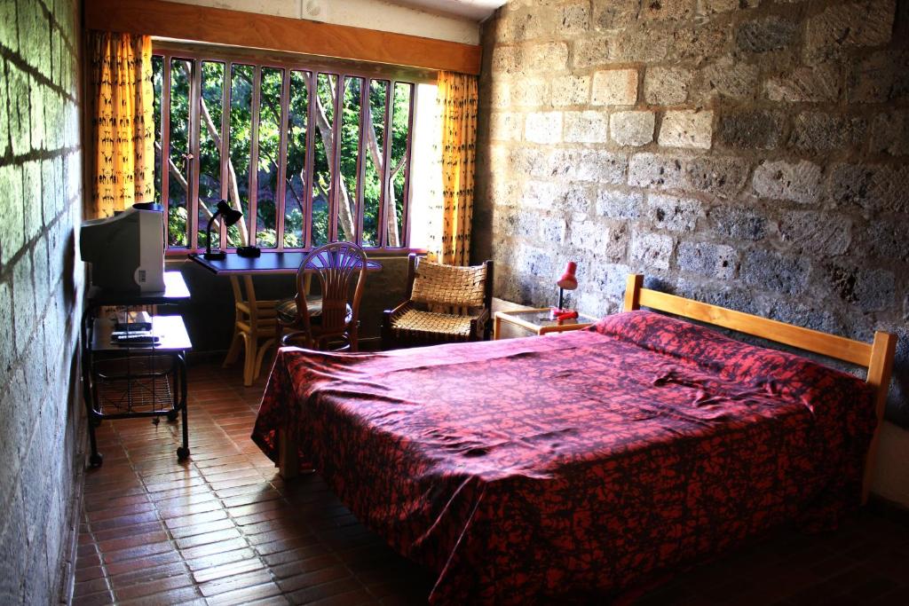 um quarto com uma cama, uma secretária e uma janela em Villa Rock Stop Falls em Nairobi
