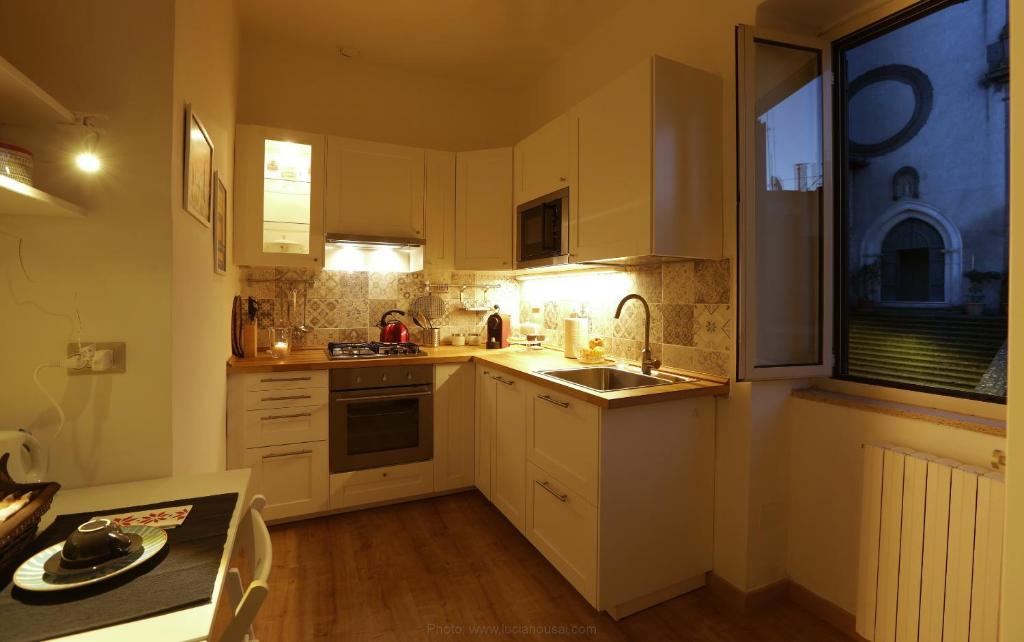 a kitchen with white cabinets and a sink and a table at Casa della nonna sulla francigena in Campagnano di Roma