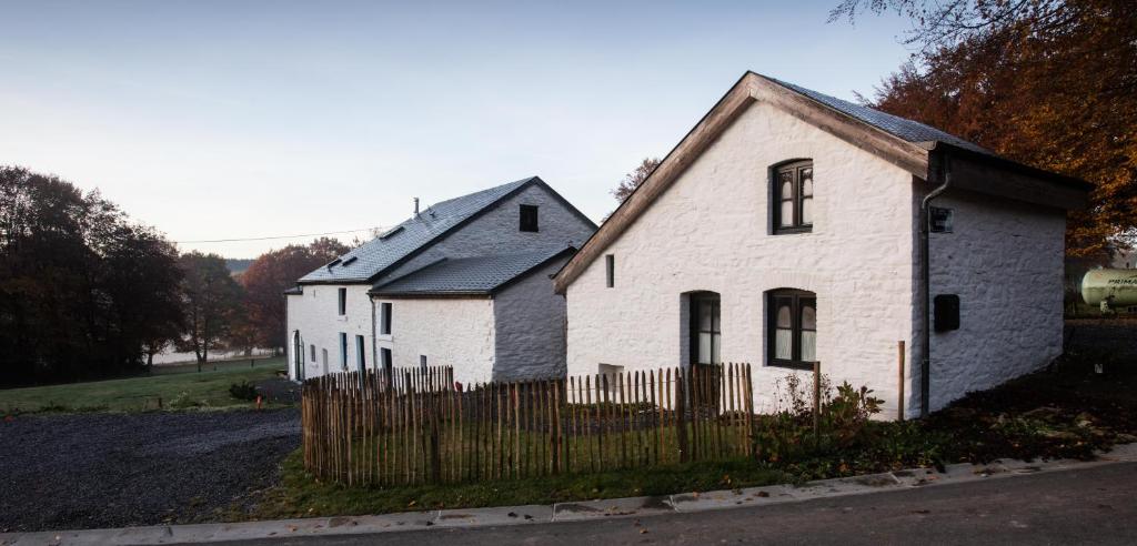 an old white house with a wooden fence at B&B La Gotale in Manhay