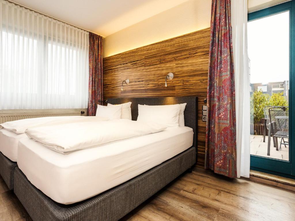 a bedroom with a large bed and a large window at Hotel & Wirtshaus Hansen in Bergisch Gladbach