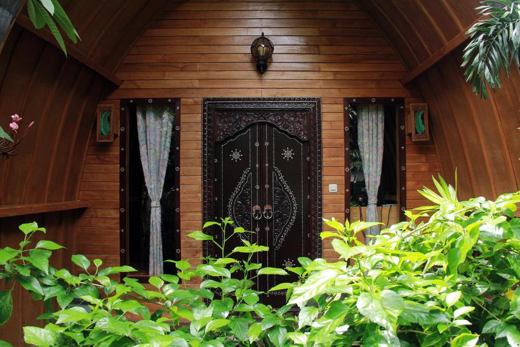 a black door on a wooden house with plants at Banana Leaf Bungalow in Gili Trawangan