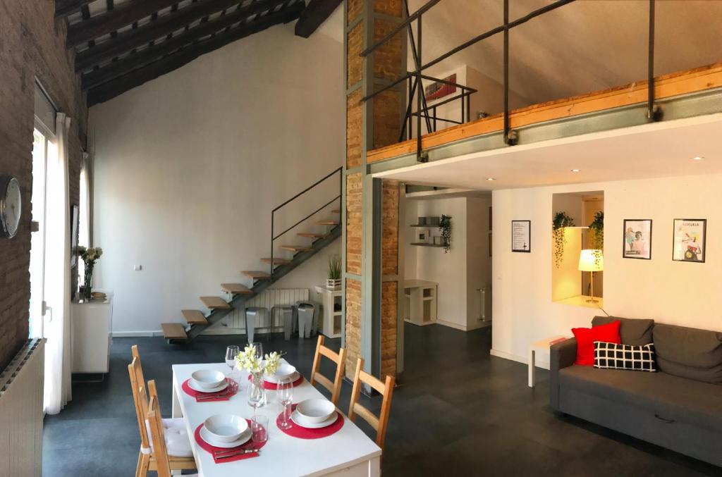 ein Zimmer mit einem Tisch, einem Sofa und einer Treppe in der Unterkunft Atico Loft Ruzafa in Valencia