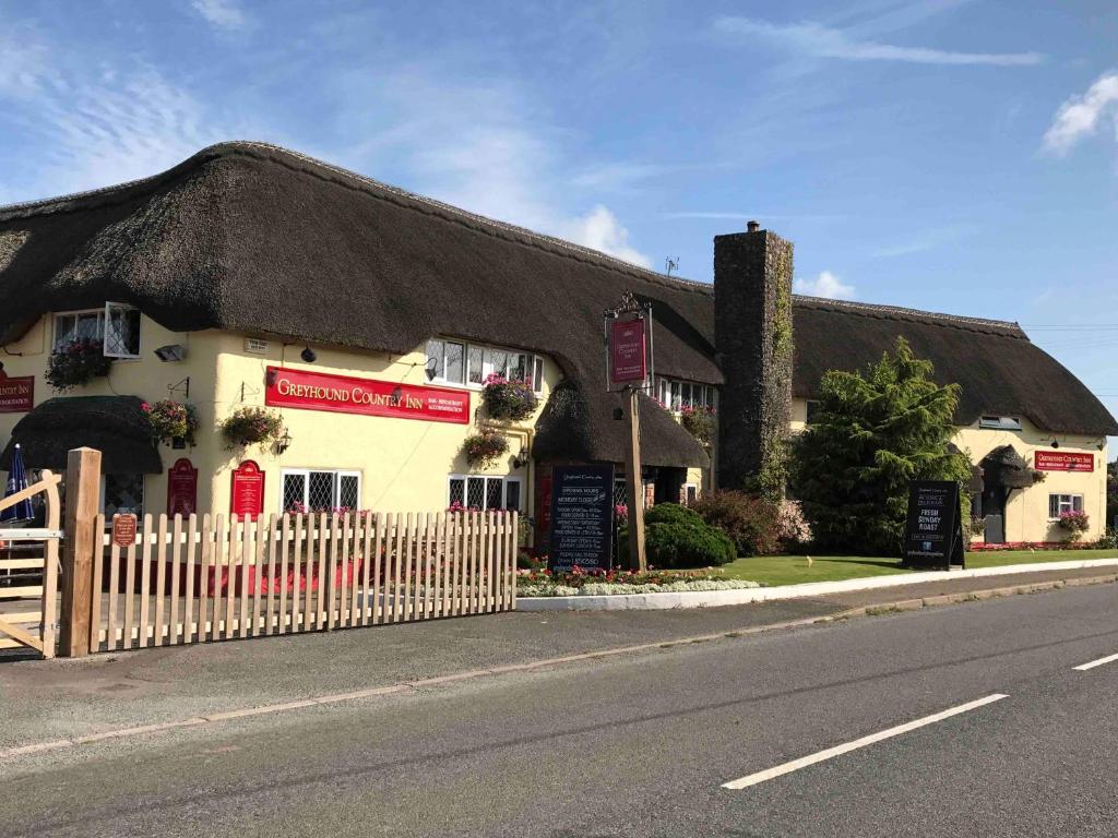 a building with a thatched roof on a street at Greyhound Country Inn in Honiton