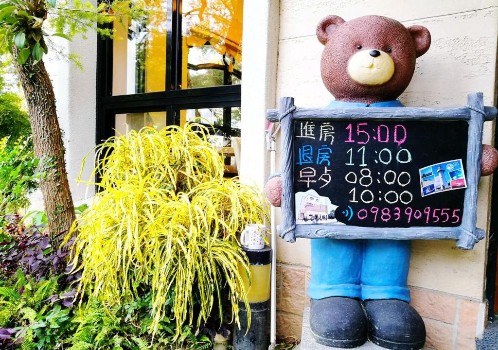 a teddy bear holding a sign in front of a house at Borabora B&amp;B in Nanwan