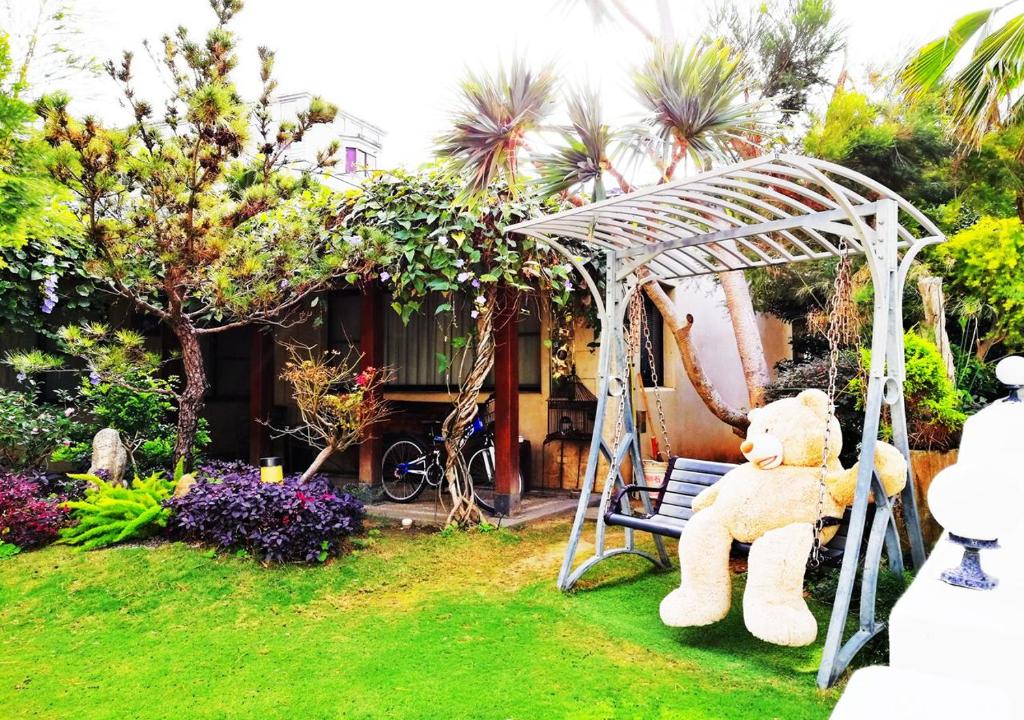 a teddy bear sitting on a swing in a yard at Borabora B&amp;B in Nanwan