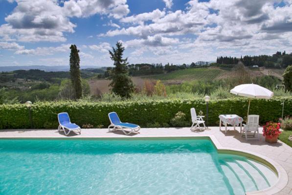 basen z krzesłami, stołem i parasolem w obiekcie Monolocale il vecchio fienile w mieście San Gimignano