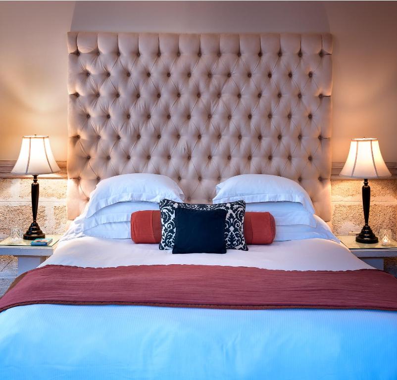 a large bed with a large headboard and pillows at Little Arches Boutique Hotel - Adults Only in Christ Church