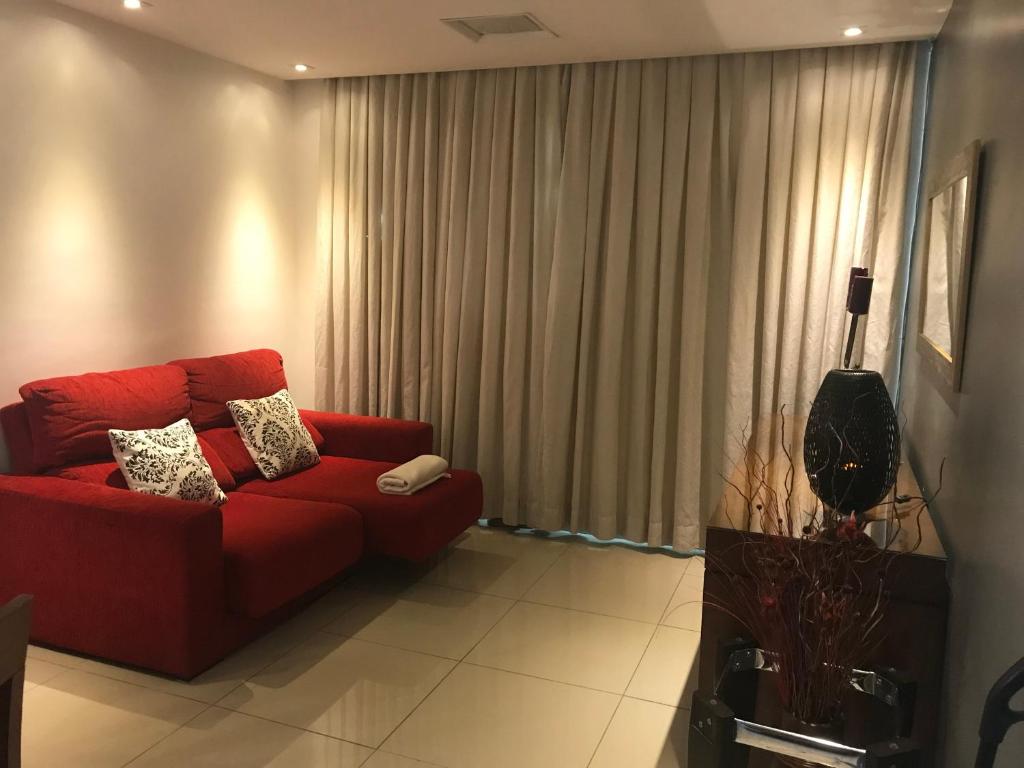 um sofá vermelho numa sala de estar com cortinas em The Color Flat Contagem em Contagem