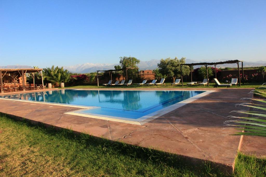 una gran piscina con sillas en un patio en Ecolodge Quaryati Marrakech, en Douar Tounsi