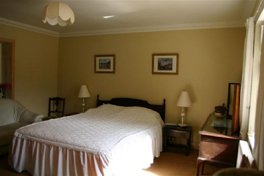 a bedroom with a bed and two tables and two lamps at Woodcroft Cottage in Ayr