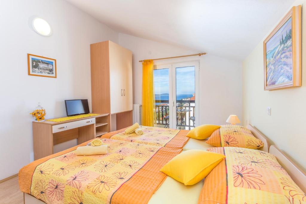 two beds in a bedroom with a desk and a television at Apartments and Rooms Ivanović in Hvar