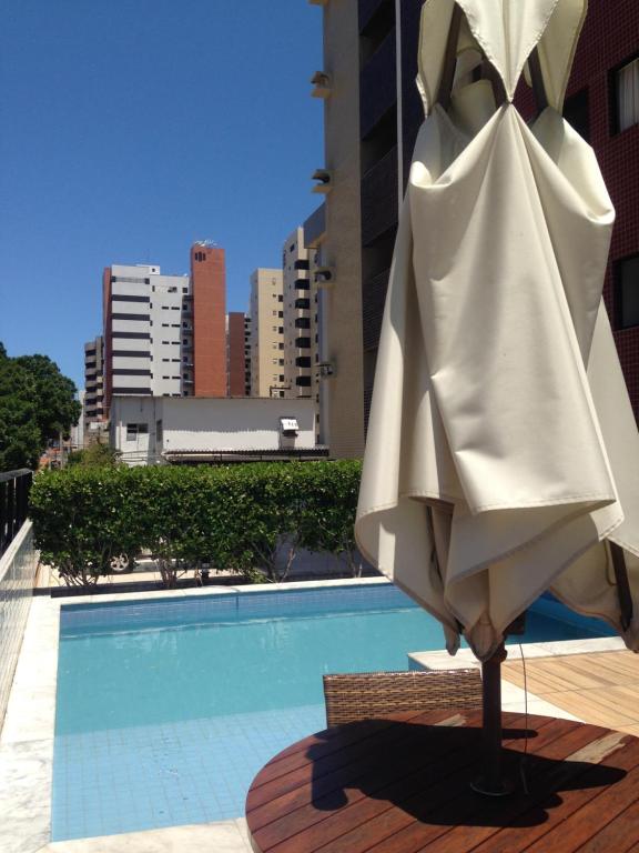 ein weißer Regenschirm neben einem Pool in der Unterkunft Apartamento Ponta Verde - SOHO in Maceió