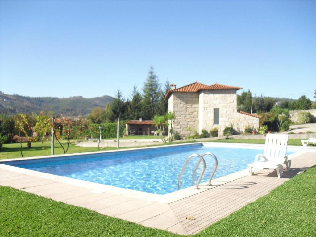 a swimming pool with a chair and a house at Casa do Pomarelho in Póvoa de Lanhoso