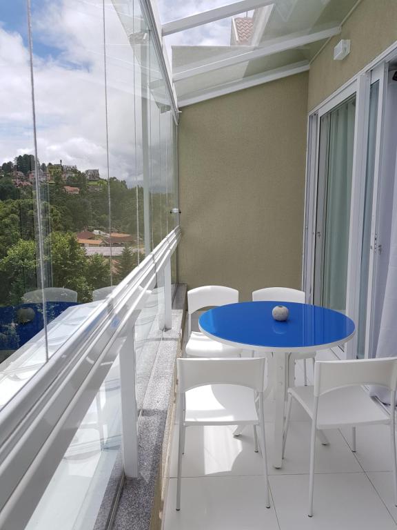 balcón con mesa azul y sillas blancas en Gaudi Loft Design, en Campos do Jordão