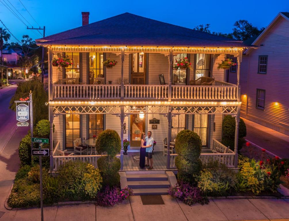 una mujer parada frente a una casa con luces en Carriage Way Inn Bed & Breakfast Adults Only - 21 years old and up en St. Augustine