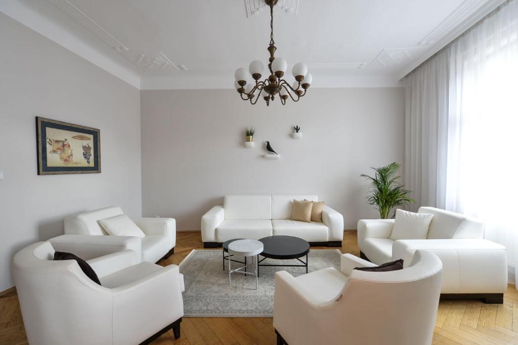 a living room with white furniture and a chandelier at Art Nouveau Residence in Prague