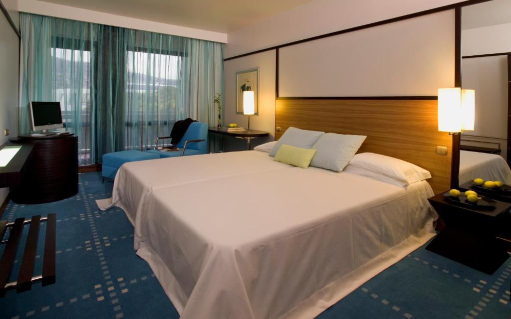 a hotel room with a large bed and a desk at Pestana Casino Park Hotel & Casino in Funchal