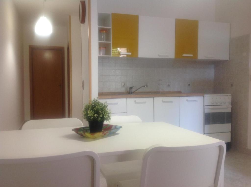 a kitchen with white cabinets and a table with white chairs at fabrizio e caterina in San Vito lo Capo