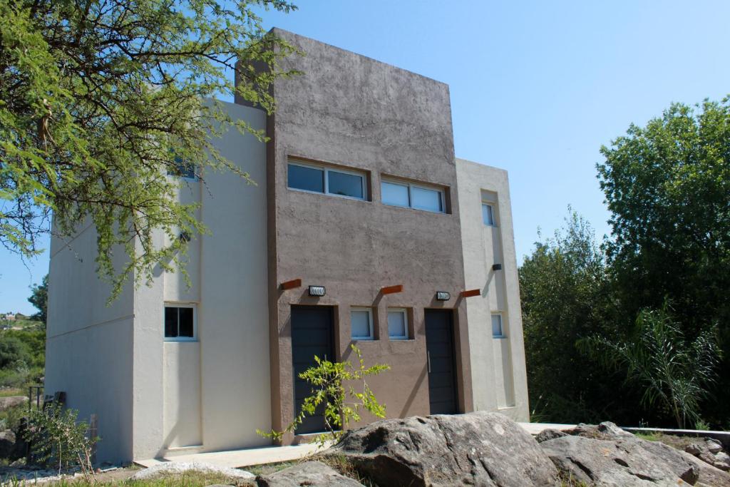 ein Gebäude mit einem großen Felsen davor in der Unterkunft Cabañas Paititi in Villa Carlos Paz
