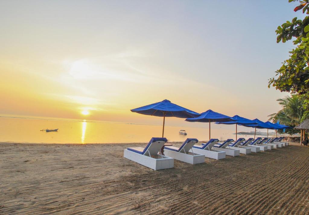 サヌールにあるインナ シンドゥ ビーチ ホテル＆リゾートの浜辺の椅子・傘