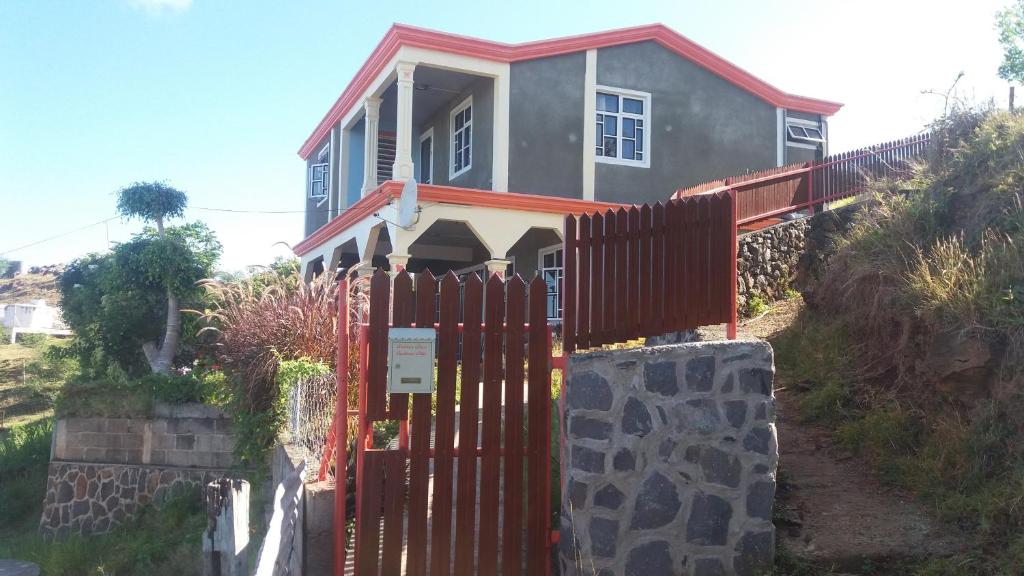 a house with a red fence in front of it at Résidence Véronia in Rodrigues Island