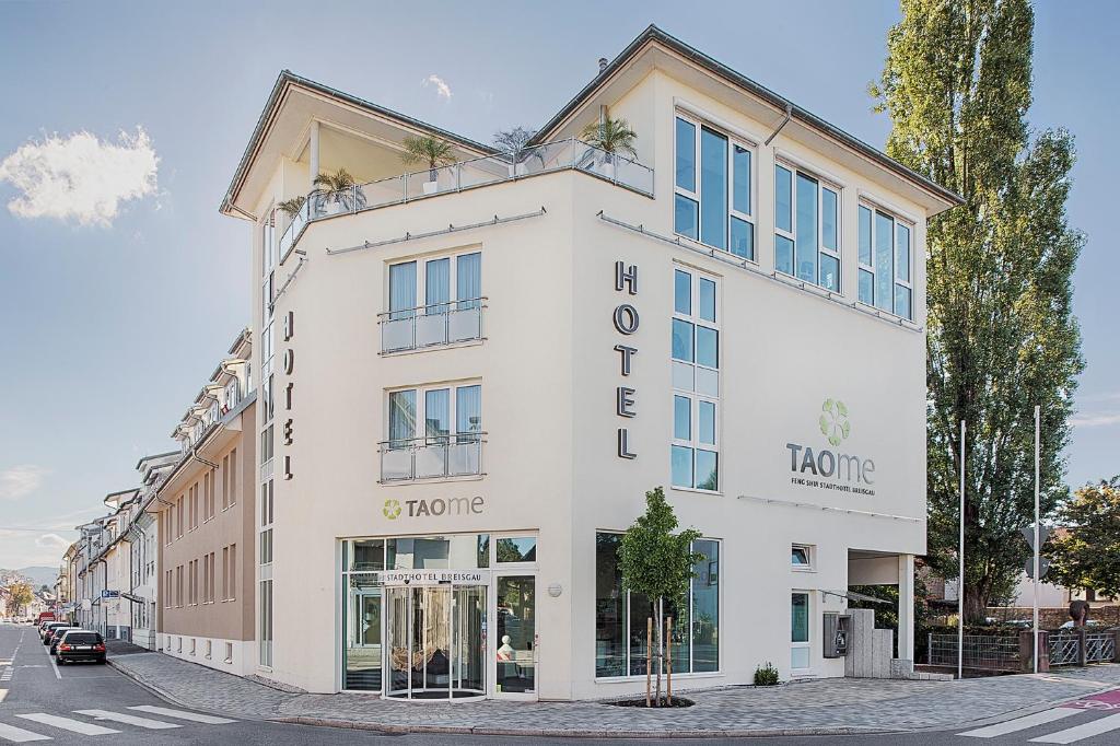 a large white building on a city street at Taome Feng Shui Stadthotel Breisgau in Emmendingen