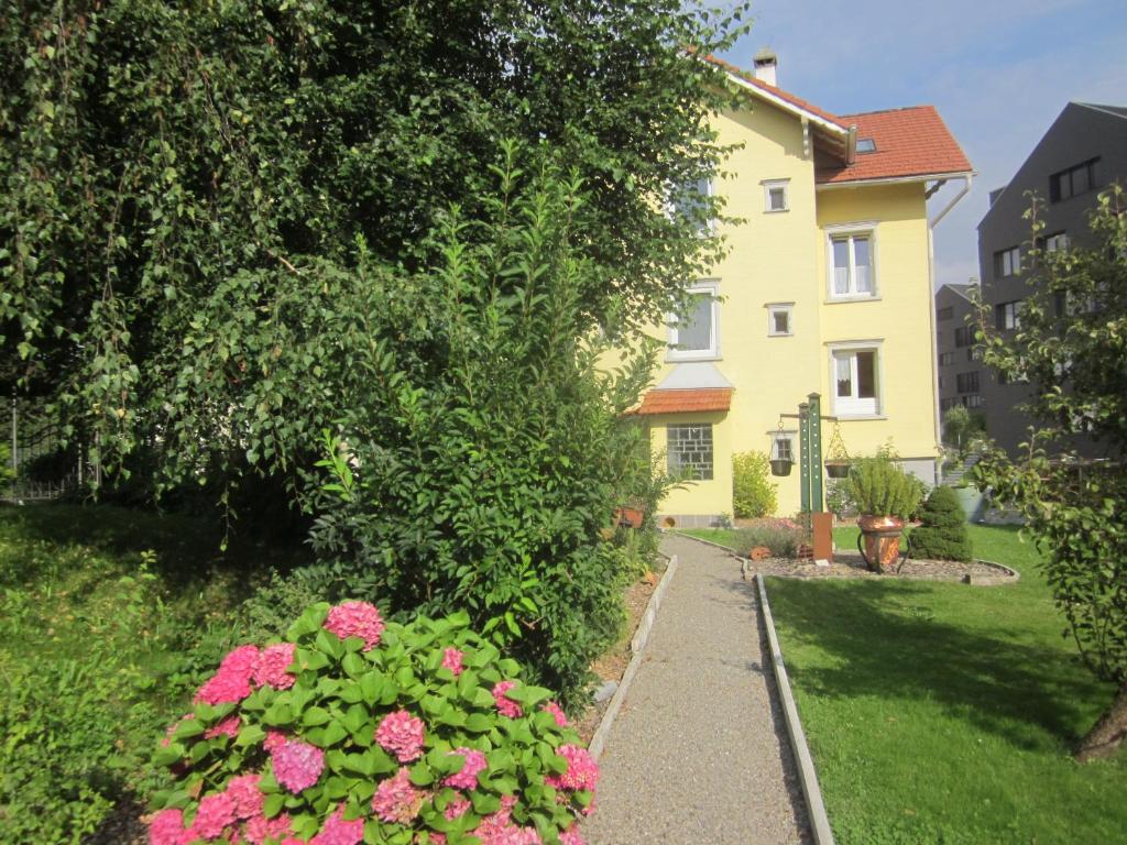 uma passarela em frente a uma casa com flores cor-de-rosa em Haus Basilea em Wolfhalden 