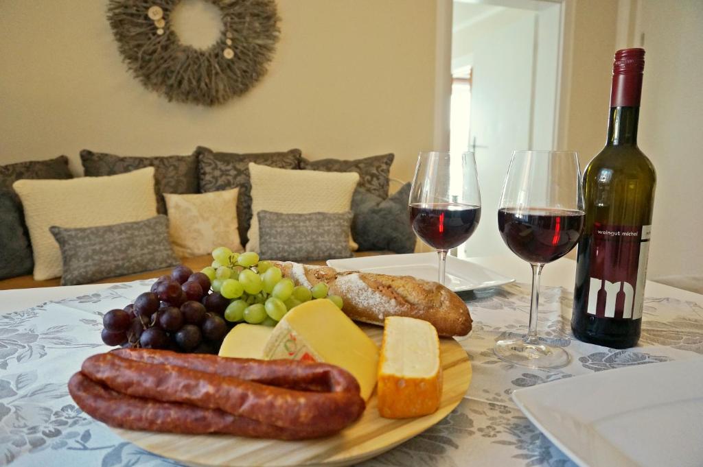 una mesa con un plato de salchichas, queso y vino en Ferienwohnung Scheib, en Bad Sobernheim