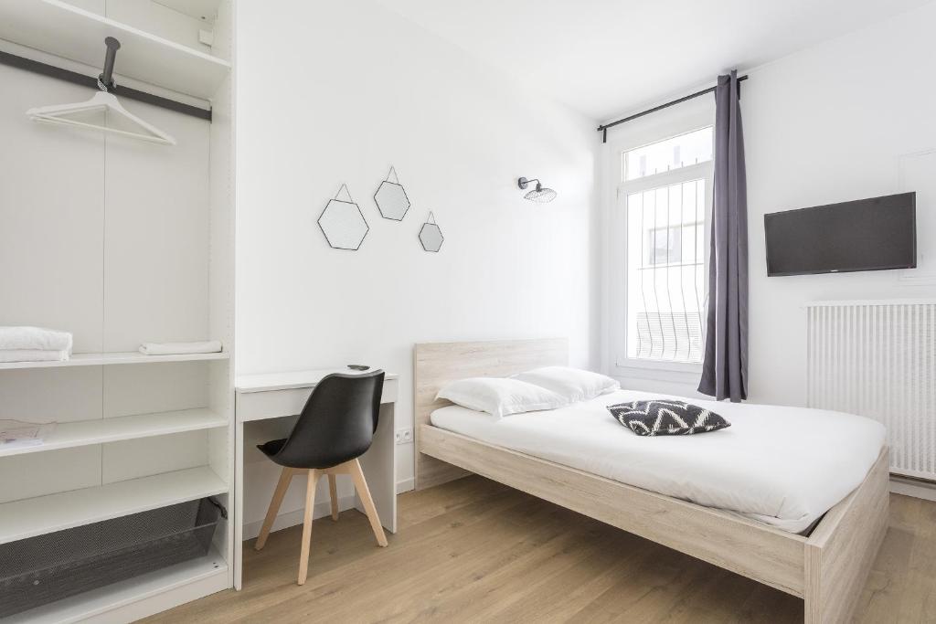 a white bedroom with a bed and a chair at Gare Saint Roch - Podshare in Montpellier