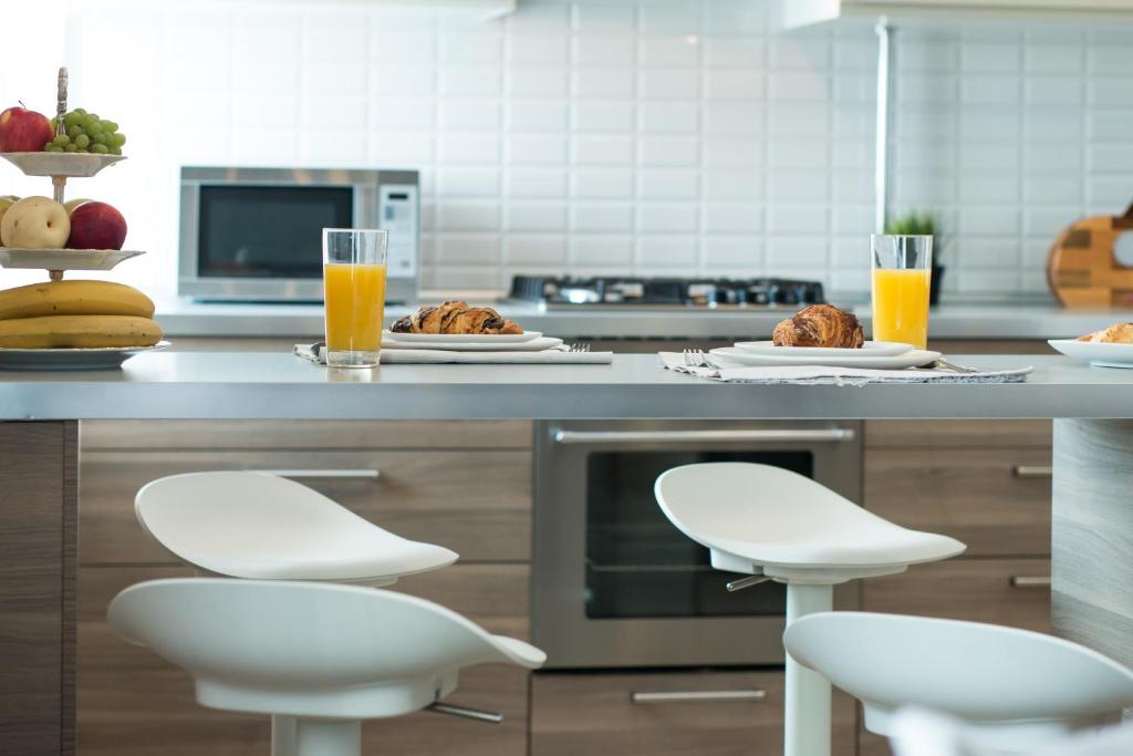 a kitchen with white stools and food on a counter at Business Penthouse in the center in Kazan