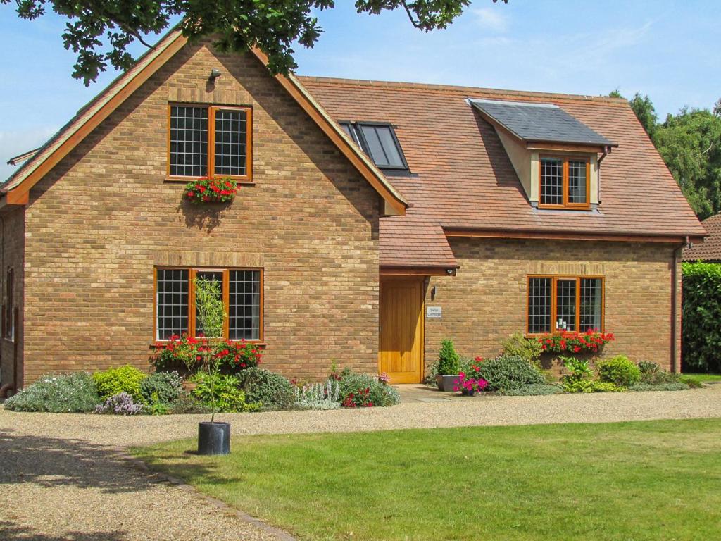 a brick house with flowers in the front yard at Swiss Cottage in Aldringham