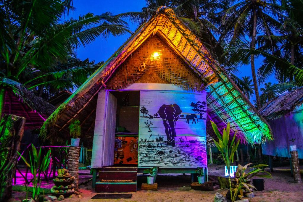 a thatch roofed hut with a lit up facade at Rosa Shashi Cabanas in Galle