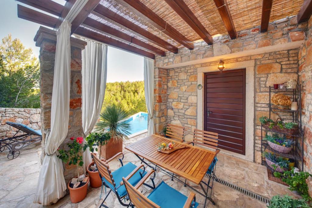 a patio with a wooden table and chairs on a porch at Villa Rosa in Vrboska